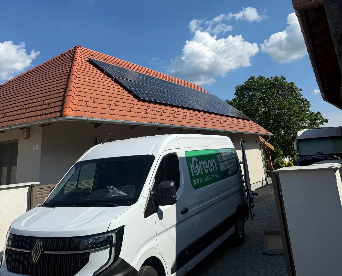 Az iGreen kivitelezői autója egy napelemes rendszerrel felszerelt családi háznál